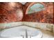 Corner bathtub with textured wall and arched window at 30174 Glen Eyrie Dr, Evergreen, CO 80439