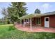 Inviting backyard patio with red brick, lush lawn, mature trees, and partially covered seating area at 6587 S Clarkson St, Centennial, CO 80121