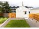 View of a fenced-in backyard with a small lawn, stone path, and a garage at 1101 S Dahlia St, Denver, CO 80246