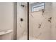 Modern shower with marble-look tile and sleek black hardware and a convenient corner shelf at 1101 S Dahlia St, Denver, CO 80246