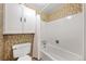 Full bath with a floral accent wallpaper, white tiled walls, a toilet, and a tub with shower at 3821 S Magnolia Way, Denver, CO 80237