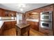This kitchen features a brick archway, stainless steel appliances, and wood cabinets with glass insets at 3821 S Magnolia Way, Denver, CO 80237