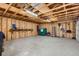 View of the unfinished garage with wood beams, concrete flooring, and a shelf with tools at 1120 Xenia St, Denver, CO 80220