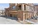 Exterior of a townhome showcasing brick accents, double garage, and a small balcony with iron railings at 9374 Loggia St # D, Highlands Ranch, CO 80126
