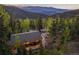 Aerial view of a home surrounded by lush greenery with mountain views in the background at 375 Castlewood Dr, Evergreen, CO 80439