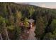 An aerial view of a cozy home surrounded by lush greenery with a private driveway at 375 Castlewood Dr, Evergreen, CO 80439