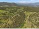 Expansive aerial view of a property boasting green acreage, mature trees, and mountain views at 3800 Lakota Rd, Indian Hills, CO 80454