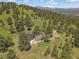Breathtaking aerial view of a secluded stone home in a forested area with mountain views under a clear blue sky at 3800 Lakota Rd, Indian Hills, CO 80454