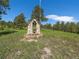 Stone bell tower artfully built in a field of native grass, framed by majestic trees and blue sky, serene landscaping at 3800 Lakota Rd, Indian Hills, CO 80454