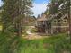 Exterior view with deck, stone foundation and mature trees at 3800 Lakota Rd, Indian Hills, CO 80454