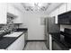 Well-lit kitchen featuring modern appliances, sleek black countertops and backsplash and light wooden flooring at 1960 S Xanadu Way # 208, Aurora, CO 80014