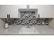 Close-up of the kitchen sink area showcasing the mosaic backsplash and countertop space at 1960 S Xanadu Way # 208, Aurora, CO 80014