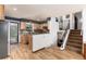 Modern kitchen with wooden cabinets, stainless steel appliances, and open floorplan with staircase access at 4917 S Xenophon Way, Morrison, CO 80465