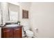 Charming half bathroom with dark cabinets, a sink, a toilet, and decor at 12997 Wyandot Way, Westminster, CO 80234