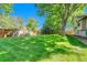 An expansive backyard featuring a lush green lawn and mature trees, fully enclosed by a wood fence at 5543 S Kenton Ct, Englewood, CO 80111