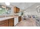 Well-designed kitchen with natural light, white appliances, warm wood cabinetry, and access to the dining area at 5543 S Kenton Ct, Englewood, CO 80111