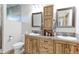Bathroom featuring double sink vanity with wood cabinets, tile backsplash, and decorative mirrors at 11499 County Road 40 1/2 Rd, Platteville, CO 80651