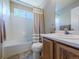 Clean bathroom featuring a tiled shower over tub, and a sink in vanity with oak colored wood at 5369 Creek Way, Parker, CO 80134