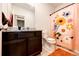 Well-lit bathroom featuring a granite countertop, dark wood cabinets, and a decorative floral shower curtain at 316 Maple St, Bennett, CO 80102