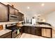Modern kitchen with stainless steel appliances, granite countertops, and dark wood cabinetry at 316 Maple St, Bennett, CO 80102
