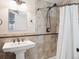 Updated bathroom featuring a pedestal sink, tiled walls, and a shower with a white curtain at 9816 S Holland St, Littleton, CO 80127