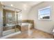 Bright bathroom with a glass-enclosed shower, soaking tub, neutral tile, and lots of natural light at 10822 E 28Th Pl, Denver, CO 80238