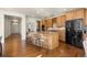 Open kitchen boasts wood cabinets, island with seating, and sleek black appliances, all on hardwood floors at 10822 E 28Th Pl, Denver, CO 80238