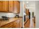 Long kitchen with wood cabinets, granite countertops, stainless appliances, and hardwood floors leading to dining at 10822 E 28Th Pl, Denver, CO 80238