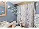 Full bathroom with a shower/tub combo, blue walls, and decorative seashell art at 4533 S Devinney St, Morrison, CO 80465