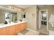Bright bathroom featuring dual sinks, wood cabinets, large mirror, and updated lighting fixtures at 9786 Malachite Ct, Parker, CO 80134