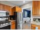 This open kitchen has wood cabinets and stainless steel appliances next to a blue dining room at 2271 Holly St, Denver, CO 80207