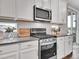 Bright kitchen featuring stainless steel appliances, white cabinets and modern backsplash tiles at 4552 S Perth Ct, Aurora, CO 80015