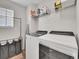 Bright laundry room featuring modern appliances and storage shelving at 4552 S Perth Ct, Aurora, CO 80015