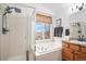 Bright bathroom featuring double sinks, a soaking tub, and a shower at 15776 E 107Th Way, Commerce City, CO 80022