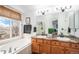 Bright bathroom featuring double sinks, a soaking tub, and a window with neighborhood views at 15776 E 107Th Way, Commerce City, CO 80022