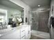 Elegant bathroom featuring a double vanity, large mirror, and walk-in shower with tiled surround at 249 E 4Th St, Berthoud, CO 80513