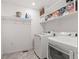Laundry room with white shelving, cleaning supplies, and modern washer and dryer units at 9590 Sedalia St, Commerce City, CO 80022