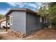 Charming exterior view of the home featuring gray siding, wooden beams, and neatly stacked firewood at 192 Little Creek Rd, Idaho Springs, CO 80452