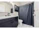 Updated bathroom with dark vanity, modern fixtures, decorative mirror, white marble floor and tiled shower with dark curtain at 5977 S Rock Creek Dr, Castle Rock, CO 80109