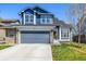 Inviting two-story home boasts a blue exterior, stone accents, a gray garage door, and a well-manicured lawn at 5977 S Rock Creek Dr, Castle Rock, CO 80109