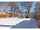 Charming home with a detached garage is showcased in a snow-covered yard, complemented by a welcoming front porch at 2918 Ames St, Wheat Ridge, CO 80214