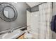 Cozy bathroom with a shower-tub combination and a round decorative mirror at 10774 Chadsworth Ln, Highlands Ranch, CO 80126