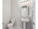 Half bathroom featuring a pedestal sink, toilet, modern lighting, and neutral tones at 13275 E Caley Pl, Centennial, CO 80111