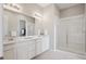 Modern bathroom with double sinks, white cabinets, quartz countertops, and a glass-enclosed shower at 13275 E Caley Pl, Centennial, CO 80111