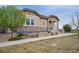 Attractive home with tan siding and stone accents, surrounded by well-maintained landscaping and a spacious yard at 13275 E Caley Pl, Centennial, CO 80111