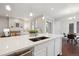 Island seating overlooks the living area with modern finishes, sink, dishwasher, and pendant lighting at 13275 E Caley Pl, Centennial, CO 80111