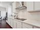 Modern kitchen design with sleek cooktop, quartz counters, stainless hood, and abundant white cabinet storage at 13275 E Caley Pl, Centennial, CO 80111