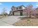 Charming two-story home with a three-car garage, and beautiful landscaping with a tree in full pink bloom at 4830 S Versailles St, Aurora, CO 80015