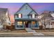 Charming two-story home featuring a welcoming front porch and red shutters against a blue exterior at dusk at 3269 Uinta St, Denver, CO 80238