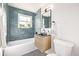 Updated bathroom with teal tile, floating vanity, and a bathtub at 5550 E Thrill Pl, Denver, CO 80207